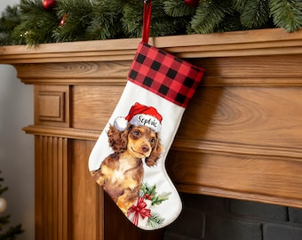 May include: White Christmas stocking with a red and black buffalo plaid cuff. The stocking features a watercolor illustration of a dachshund wearing a Santa hat with the name "Sophie". Holly and a red bow are also depicted.