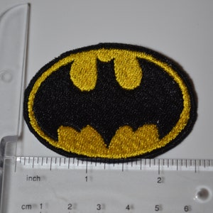 Op de afbeelding: Een geborduurde strijk-op patch met het Batman-logo. De patch is zwart en geel en ongeveer 5 cm breed.