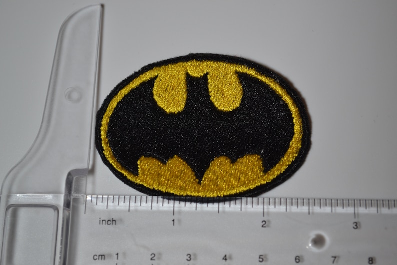 Op de afbeelding: Een geborduurde strijk-op patch met het Batman-logo. De patch is zwart en geel en ongeveer 5 cm breed.