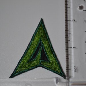Op de afbeelding: Groen en zwart geborduurd pijl-patch, ongeveer 5 cm hoog.
