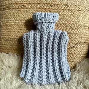 Könnte beinhalten: Ein hellblauer gestrickter Wärmflaschebezug mit Rippenstruktur.
