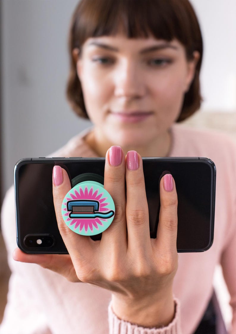 May include: A turquoise blue phone grip with a pink flower design and a cartoon illustration of a toothbrush and toothpaste.