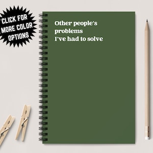 以下が含まれることがあります： 白い文字で「Other people's problems I've had to solve」と印刷された、濃い緑色のスパイラルバインダーノート