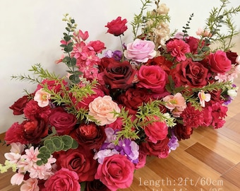 May include: A vibrant floral arrangement featuring a variety of red, pink, and purple roses, carnations, and other flowers. The arrangement is 2 feet long, 14 inches wide, and 1.8 feet high. Green foliage accents the colorful blooms, creating a lush display.