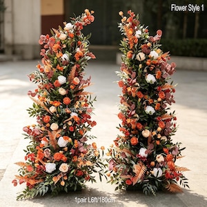 Peut inclure: Deux grands arrangements floraux verticaux composés de fleurs blanches, orange et rouge foncé, de feuillage vert et de feuilles rappelant des fougères. Le texte "Flower Style 1" et "1pair L6ft/180cm" est visible. Ces compositions forment une paire.