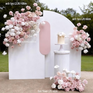 May include: A white wedding backdrop with a pink accent, decorated with pink and white floral arrangements. A small cake is on a pedestal. The text "Lackon Customization" is visible.