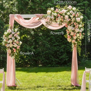 Könnte beinhalten: Ein weißer Hochzeitsbogen aus Holz, 100 cm breit und 100 cm hoch, drapiert mit durchsichtigem rosa Stoff. Der Bogen ist mit Blumenarrangements aus weißen und rosa Blumen geschmückt und steht auf einer grünen Wiese. Die Seitensäulen des Bogens sind 80 cm hoch.