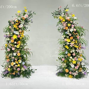 May include: Two floral archways, each 6.6 feet (200cm) tall and 1.65 feet (50cm) wide, are densely packed with a variety of colorful flowers and greenery. The arrangements feature yellow, pink, white, and purple blooms, creating a vibrant and natural display.