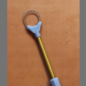 May include: A YK Mini Wire Rake Tool with a silver wire loop, light blue plastic handle, and a gold-colored metal shaft. The text "ROUND TYPE" is at the bottom. The tool is designed for crafting or art projects.