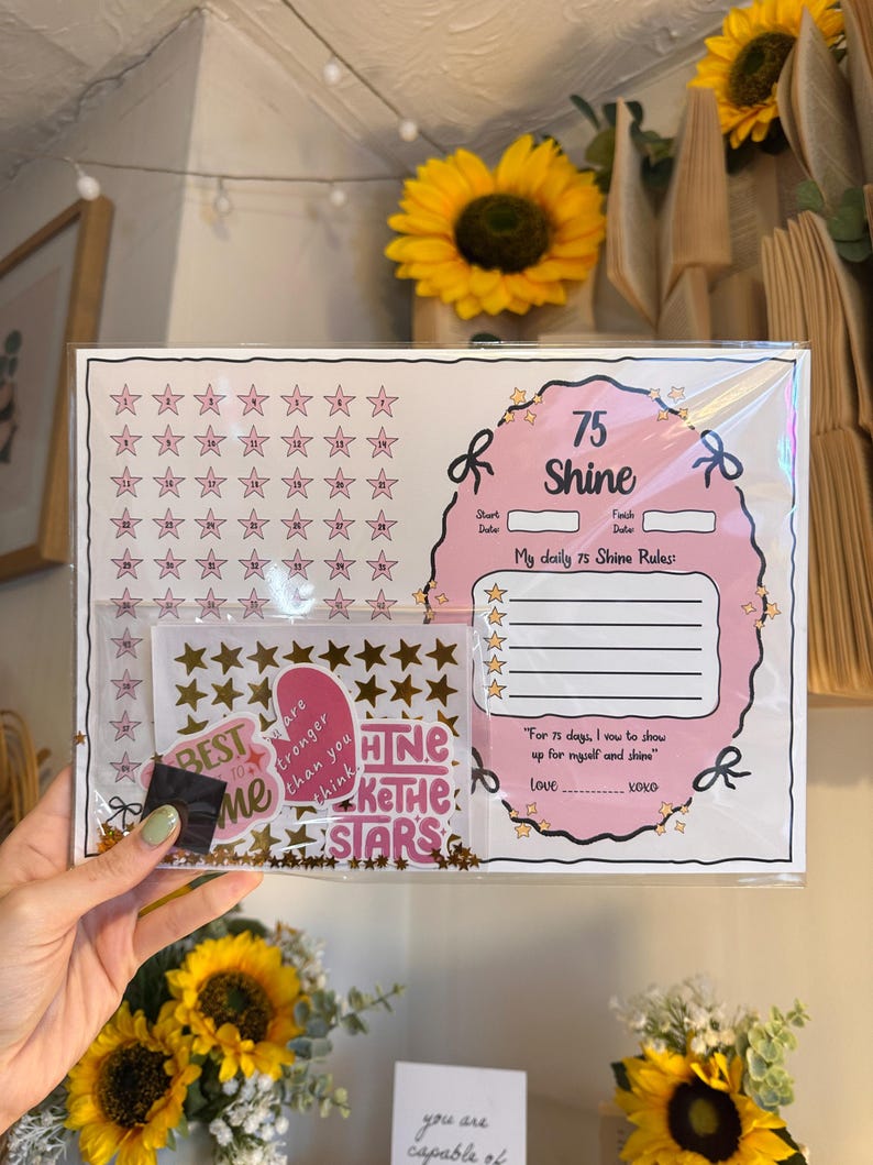 May include: A pink and white 75 Shine daily rules chart with star-shaped stickers. The chart includes space for daily rules and a motivational quote. Gold star stickers and the words "BEST ME" are also included.