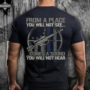 May include: Navy blue t-shirt with a graphic of a rifle inside a target, with the text "FROM A PLACE YOU WILL NOT SEE... COMES A SOUND YOU WILL NOT HEAR". The shirt also has the word "WARRIORS" at the top left.