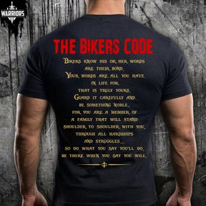May include: A black short-sleeved t-shirt featuring the red text THE BIKERS CODE at the top, followed by gold text detailing a code of conduct about honour, loyalty, and family. A small gold decorative emblem is centred at the bottom of the text.