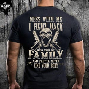 May include: A black short-sleeved t-shirt featuring a graphic print in beige. The design includes a skull, two handguns, and the text: MESS WITH ME I FIGHT BACK MESS WITH MY FAMILY AND THEY'LL NEVER FIND YOUR BODY. The shirt has a crew neckline.