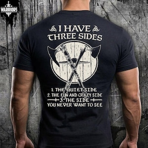 May include: A black short-sleeve t-shirt featuring a white graphic of two crossed axes over a circular shield. The text reads: I HAVE THREE SIDES, 1. THE QUIET SIDE, 2. THE FUN AND CRAZY SIDE, 3. THE SIDE YOU NEVER WANT TO SEE. A small logo is at the top.