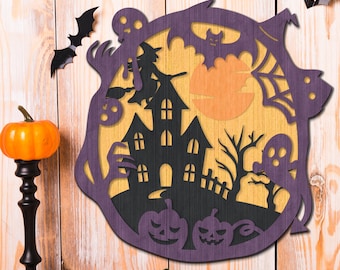 May include: A layered Halloween wooden decoration with a haunted house, pumpkins, bats, and a full moon. The design uses black, purple, and orange, creating a spooky atmosphere. Decorative pumpkins are placed in front of the wooden decoration.