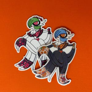 May include: Two stickers featuring a stylized character with a white body, green hair, and a pink and black floral design. The second sticker has a blue hair and orange accents. Both stickers are on an orange background.