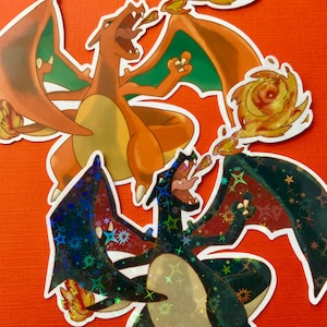 May include: Two holographic stickers of Pokemon characters, Charizard and Rayquaza. Charizard is orange and green with flames coming from its mouth. Rayquaza is black and green with a holographic finish and stars.