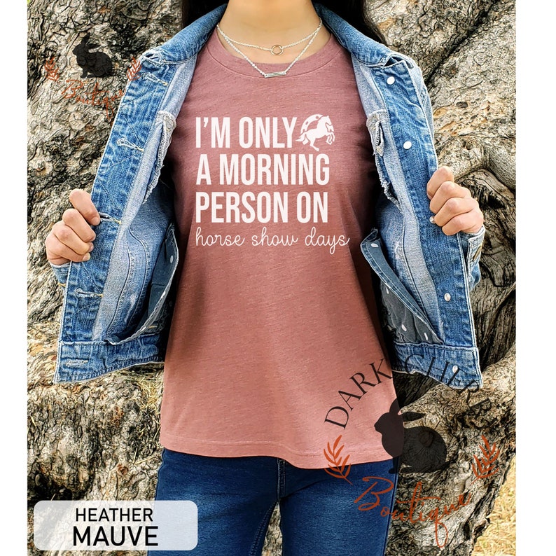 K&ouml;nnte beinhalten: Heather-Mauvefarbenes T-Shirt mit dem wei&szlig;en Text "I'M ONLY A MORNING PERSON ON horse show days". Das Shirt zeigt eine Pferde-Grafik. Das Model tr&auml;gt eine Jeansjacke und blaue Jeans. Das Shirt hat eine Heather-Mauve Farbe.