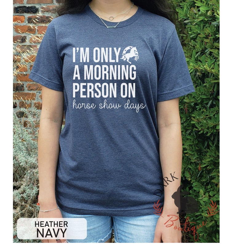 K&ouml;nnte beinhalten: Melierter marineblauer T-Shirt mit dem wei&szlig;en Text "I'M ONLY A MORNING PERSON ON horse show days". Eine wei&szlig;e Pferde-Grafik befindet sich &uuml;ber dem Text. Das T-Shirt hat einen Rundhalsausschnitt.
