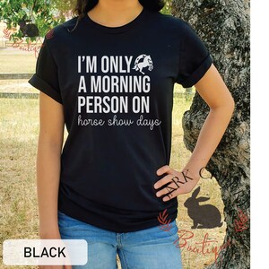 K&ouml;nnte beinhalten: Schwarzes T-Shirt mit wei&szlig;em Text, der "Ich bin nur ein Morgenmensch an Pferdeshow-Tagen" lautet. &Uuml;ber dem Text befindet sich eine wei&szlig;e Silhouette eines Pferdes.