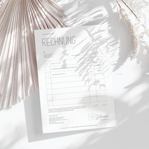May include: A white invoice form with the heading "RECHNUNG" in black text. The form includes sections for "AN", "DIENSTLEISTUNG", "PREIS", and "SUMME". The bottom of the form includes contact information for "Studio Name Here" and a logo with a camera icon.