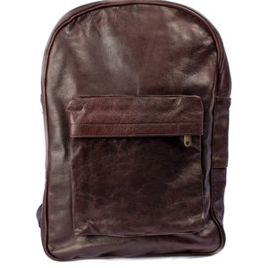 May include: A brown leather backpack with a large front pocket and a zipper closure. The backpack has a simple design and is made of high-quality leather.