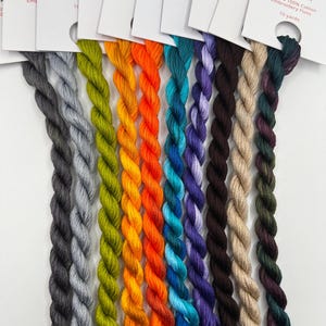 May include: A collection of colorful embroidery floss skeins in a rainbow of hues, including gray, green, orange, blue, purple, brown, and dark green. Each skein is labeled with "PIRATE + ROBIN" and "6 Strand 100% Cotton Embroidery Floss, 10 yards."