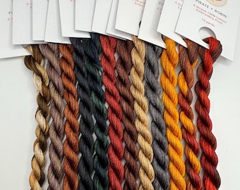 May include: A set of 12 spools of embroidery floss in various shades of brown, orange, red, green, and gray. The spools are labeled "Pirate + Robin" and "6 Strand 100% Cotton Embroidery Floss 10 yards".