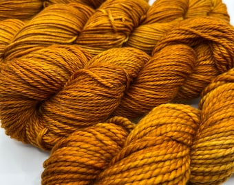 Peut inclure: Un gros plan sur une pelote de fil de couleur brun doré. Le fil est doux et moelleux, et il est parfait pour le tricot ou le crochet.