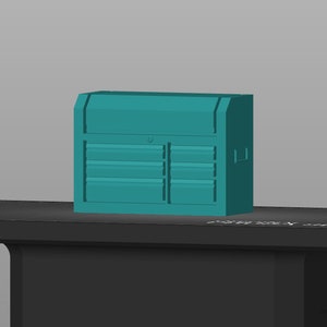 Puede incluir: Caja de herramientas de metal de color verde azulado con varios cajones. La caja de herramientas está sobre una superficie negra.