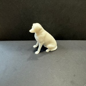 May include: A white ceramic figurine of a dog sitting with its head turned to the side.