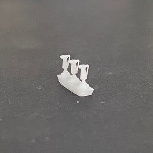 May include: A set of four white plastic candle holders, each with a simple, cylindrical design. The holders are arranged in a row on a gray surface.