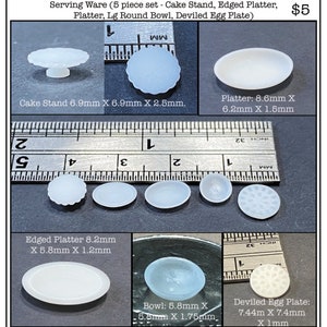 May include: A set of five miniature white ceramic serving pieces, including a cake stand, two platters, a bowl, and a deviled egg plate. The pieces are arranged on a ruler for scale. The text "Serving Ware (5 piece set - Cake Stand, Edged Platter, Platter, Lg Round Bowl, Deviled Egg Plate)" and "$5" are visible in the image.
