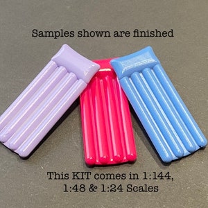 May include: Three inflatable pool floats in purple, pink, and blue. The floats are designed to look like air mattresses with multiple air chambers. The text "Samples shown are finished" and "This KIT comes in 1:144, 1:48 & 1:24 Scales" is visible in the image.