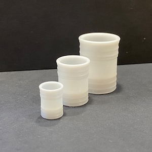 May include: Three white plastic barrels of different sizes. The barrels are cylindrical and have a smooth, matte finish.