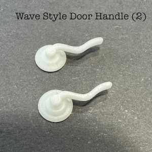 May include: Two white plastic wave style door handles. The handles are curved and have a round base.