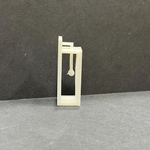 以下が含まれることがあります： 窓とドアが1つずつある小さな建物の白いプラスチックモデル。モデルは薄いプラスチックでできており、シンプルなデザインです。