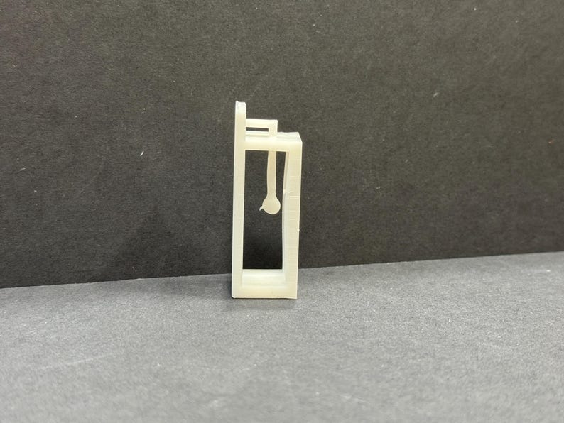 以下が含まれることがあります： 窓とドアが1つずつある小さな建物の白いプラスチックモデル。モデルは薄いプラスチックでできており、シンプルなデザインです。
