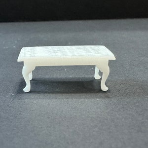 May include: White miniature table with a rectangular top and four legs. The table is made of plastic and has a smooth, matte finish.