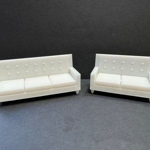 May include: Two white, tufted sofas. The larger sofa has three cushions and the smaller sofa has two cushions.