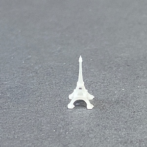 May include: A small white plastic Eiffel Tower model.