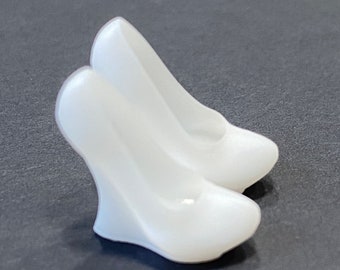 May include: A pair of white wedge heel shoes. The shoes have a smooth, glossy finish and a rounded toe. The wedge heel provides support and a modern look. The shoes are set against a dark background.