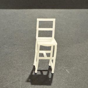 Könnte beinhalten: Ein kleiner, weißer Miniaturstuhl mit rechteckiger Rückenlehne und Sitzfläche. Der Stuhl hat vier Beine und eine Stützstruktur. Der Stuhl besteht aus einem festen Material und wirft einen Schatten auf die dunkle Oberfläche.