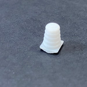 May include: A white plastic traffic cone with a square base. The cone is made of several stacked rings.