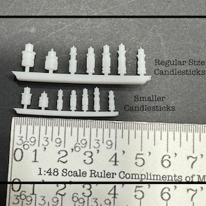 May include: Two rows of white plastic miniature candlesticks, one row labeled "Regular Size Candlesticks" and the other labeled "Smaller Candlesticks". A ruler is shown below the candlesticks with markings in inches.