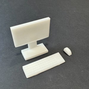 Op de afbeelding: Een witte desktopcomputer met een monitor, toetsenbord en muis. De computer is een miniatuurmodel.