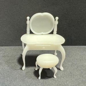 Könnte beinhalten: Weißes Schminktisch-Set mit einem runden Spiegel und einem Hocker. Der Schminktisch hat eine Schublade und geschwungene Beine. Der Hocker hat einen runden Sitz und geschwungene Beine.