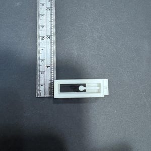 以下が含まれることがあります： 中央に小さな穴のある白いプラスチック製のドアストッパー。ドアストッパーの幅は約2.5cm、長さは約5cmです。
