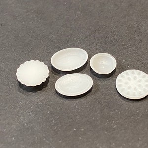 May include: Five white ceramic dishes of various shapes and sizes. The dishes are smooth and have a slightly textured surface.