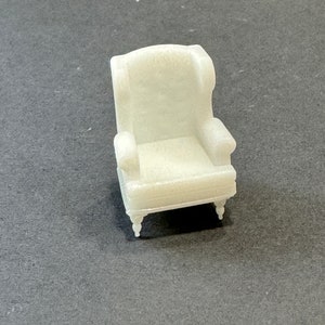May include: White miniature armchair with a high back and a tufted seat. The chair has four legs and a simple design.